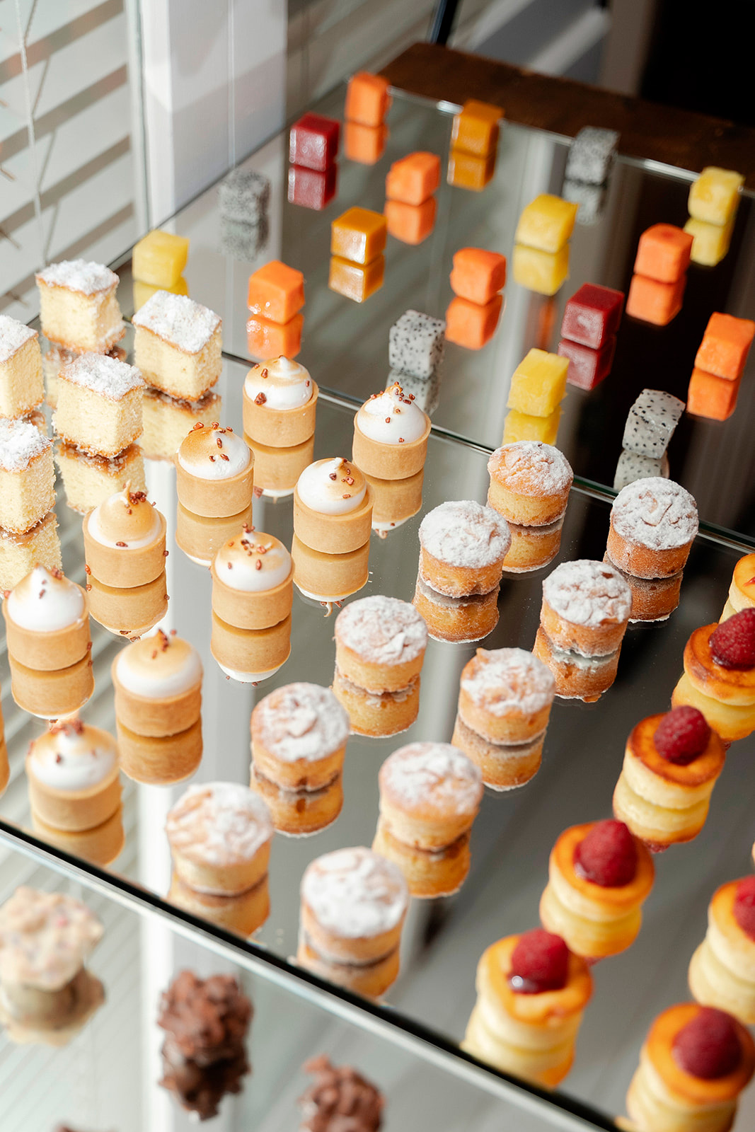 Expositor con hileras de bocados y minipostres variados