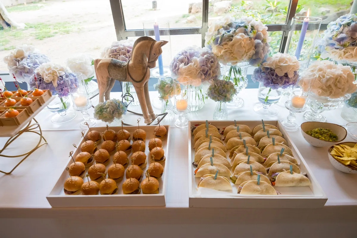 Buffet con mini hamburguesas y tacos en un bautizo